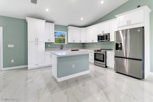 kitchen with appliances with stainless steel finishes, lofted ceiling, a center island, and white cabinets