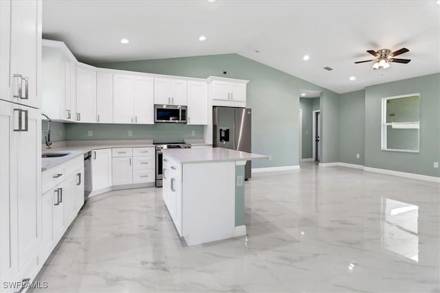 kitchen with ceiling fan, a kitchen island, white cabinetry, appliances with stainless steel finishes, and vaulted ceiling