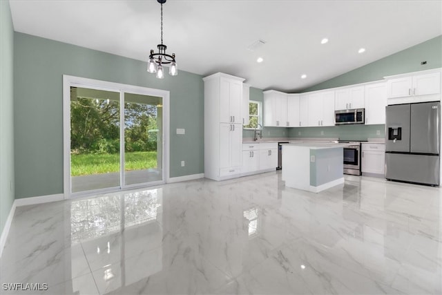 kitchen with appliances with stainless steel finishes, vaulted ceiling, white cabinetry, an inviting chandelier, and decorative light fixtures