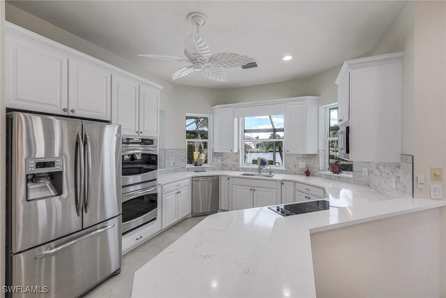 kitchen featuring decorative backsplash, white cabinetry, ceiling fan, and stainless steel appliances