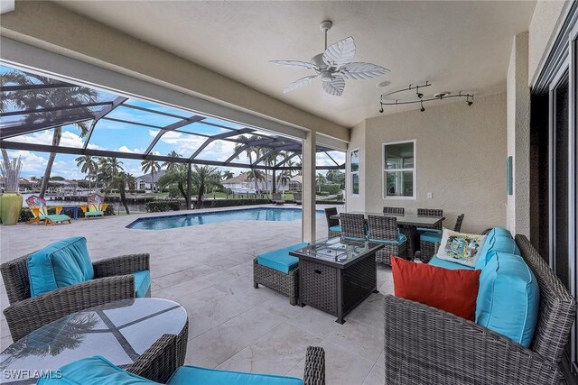 view of pool featuring a patio, glass enclosure, ceiling fan, and outdoor lounge area