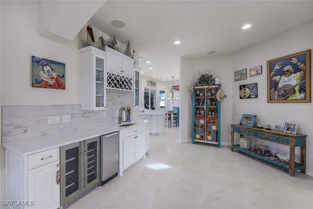 bar with sink, wine cooler, white cabinetry, and backsplash