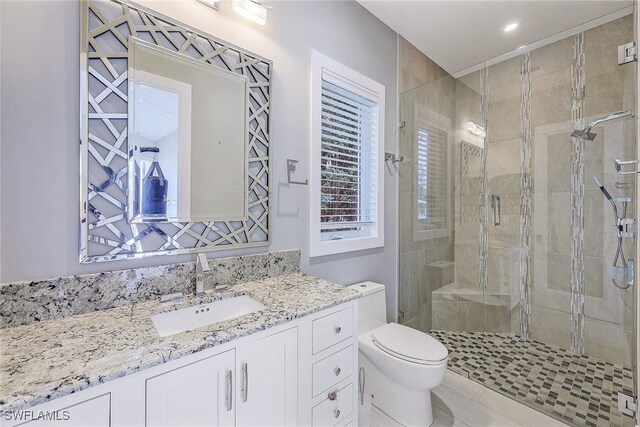 bathroom with walk in shower, vanity, and toilet