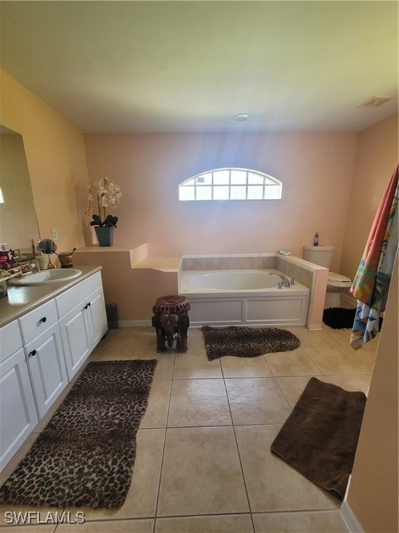 bathroom with a tub to relax in, vanity, toilet, and tile patterned floors