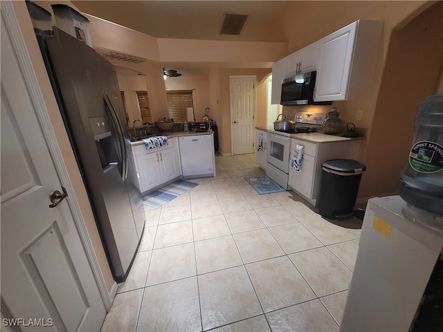 kitchen with sink, light tile patterned floors, white appliances, and white cabinetry