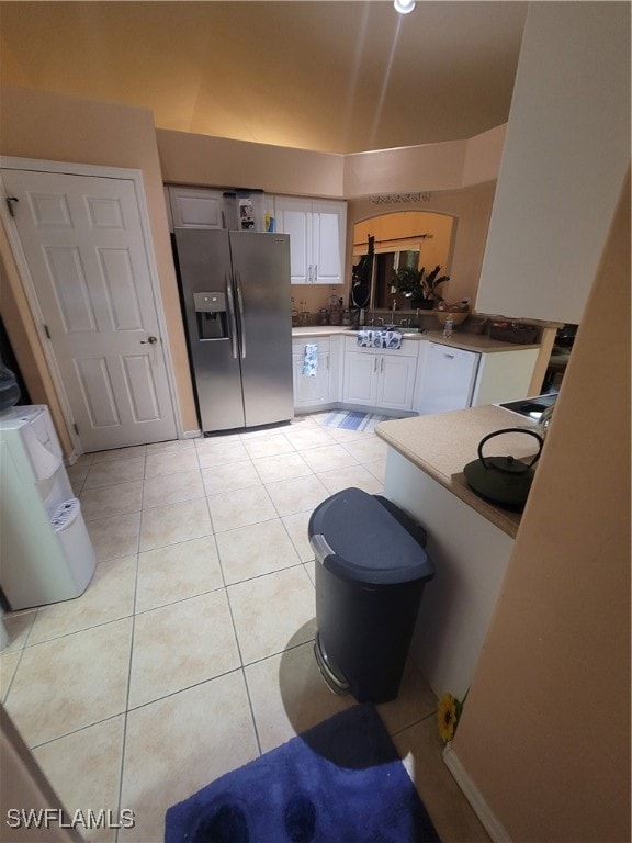 kitchen with light tile patterned floors, stainless steel fridge, and white cabinetry