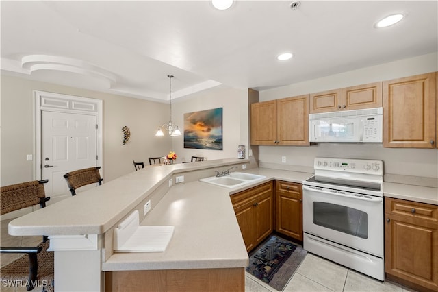 kitchen featuring hanging light fixtures, a breakfast bar, white appliances, kitchen peninsula, and sink