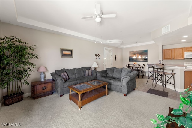 carpeted living room featuring ceiling fan and a raised ceiling