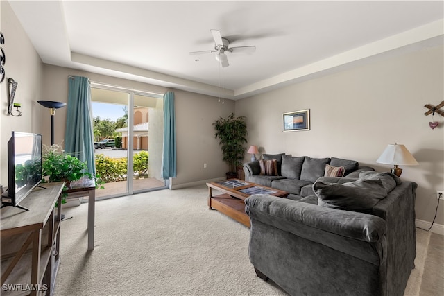 carpeted living room with ceiling fan and a raised ceiling