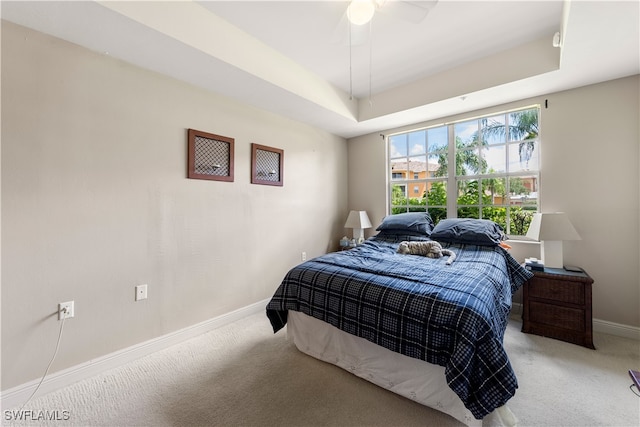 carpeted bedroom featuring ceiling fan and a raised ceiling