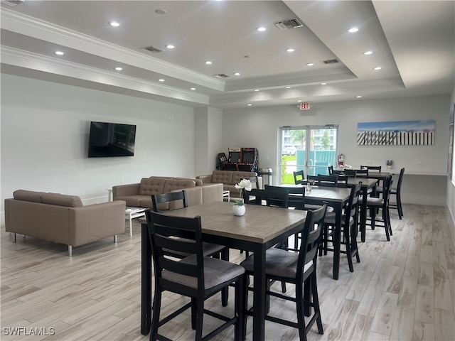 dining area with ornamental molding, light hardwood / wood-style floors, and a tray ceiling