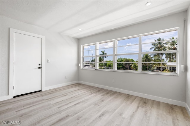 empty room featuring recessed lighting, baseboards, a textured ceiling, and light wood finished floors