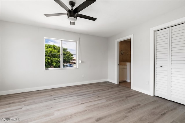 unfurnished bedroom featuring light wood-type flooring, a ceiling fan, ensuite bath, a closet, and baseboards