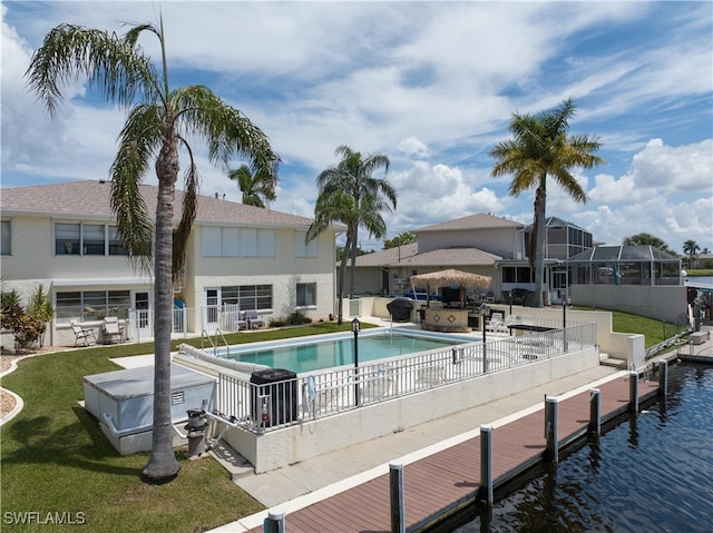 view of pool with a lawn, a dock, a water view, and a patio area