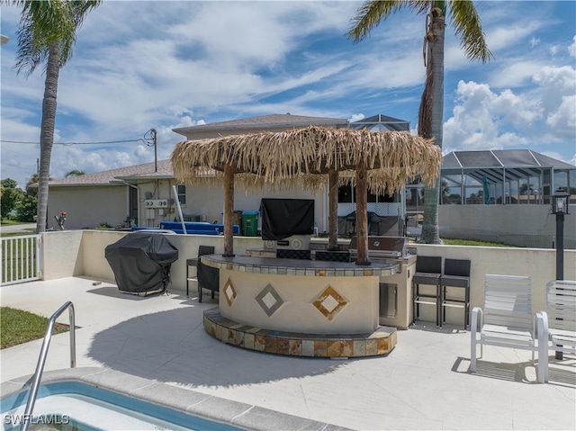 view of patio / terrace featuring outdoor wet bar, exterior kitchen, fence, and grilling area