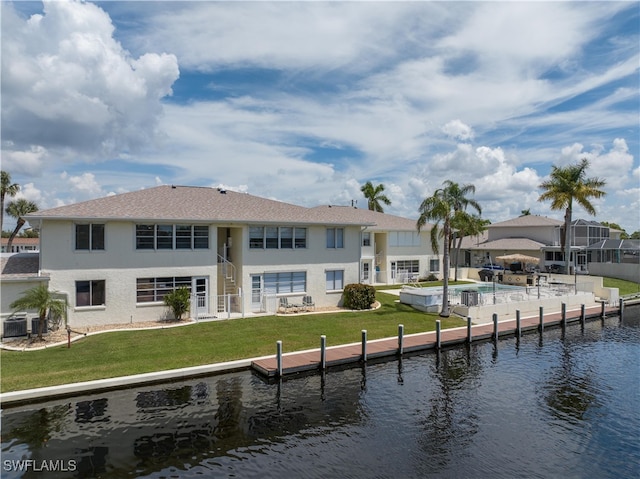 back of house featuring cooling unit, a lawn, and a water view