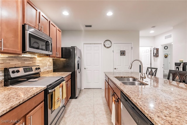 kitchen featuring light stone counters, tasteful backsplash, light tile patterned floors, stainless steel appliances, and sink