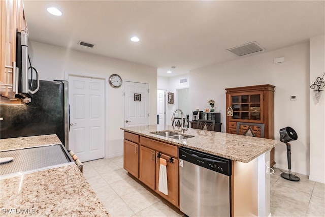 kitchen with light stone counters, light tile patterned floors, sink, a kitchen island with sink, and stainless steel appliances