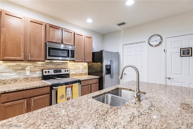 kitchen featuring light stone counters, stainless steel appliances, sink, and decorative backsplash