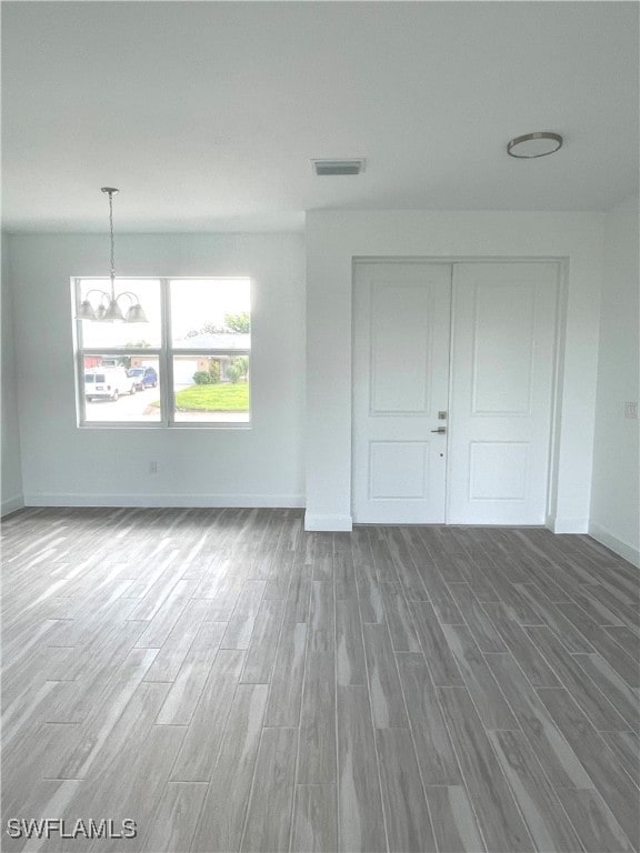 spare room with a chandelier and hardwood / wood-style floors