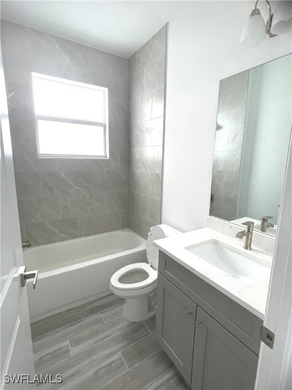 full bathroom with tiled shower / bath combo, vanity, and toilet