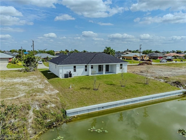 rear view of property featuring a water view, a lawn, a patio area, and central AC