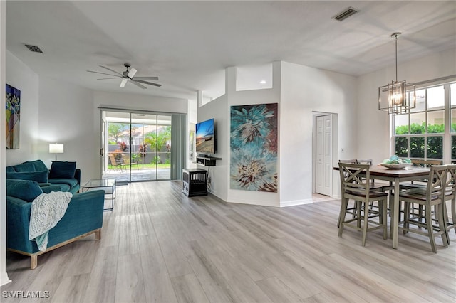 interior space featuring ceiling fan with notable chandelier and light hardwood / wood-style flooring