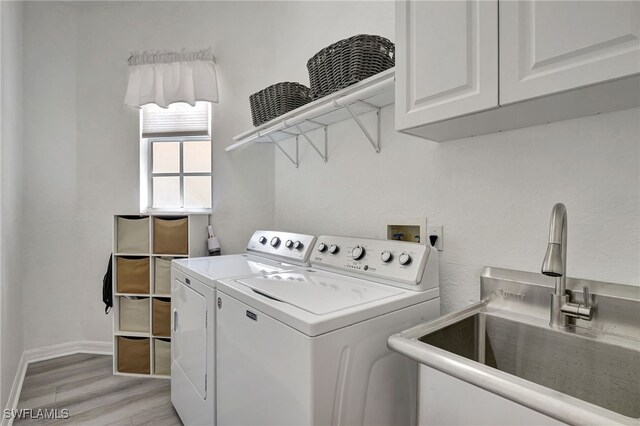 washroom with cabinets, light hardwood / wood-style flooring, washing machine and clothes dryer, and sink