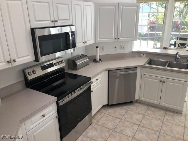 kitchen with sink, white cabinetry, stainless steel appliances, and light tile patterned flooring