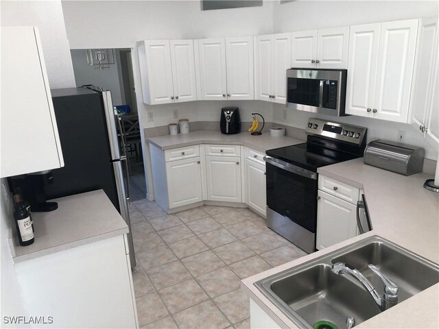 kitchen with light tile patterned floors, appliances with stainless steel finishes, sink, and white cabinetry