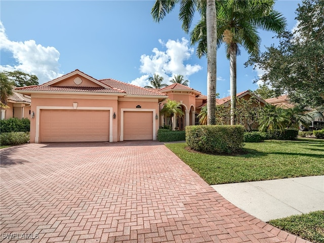 mediterranean / spanish home with a garage and a front lawn