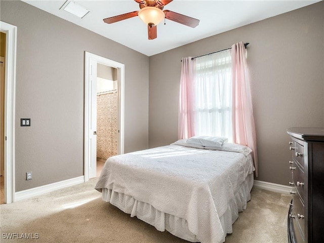 bedroom with connected bathroom, light colored carpet, and ceiling fan