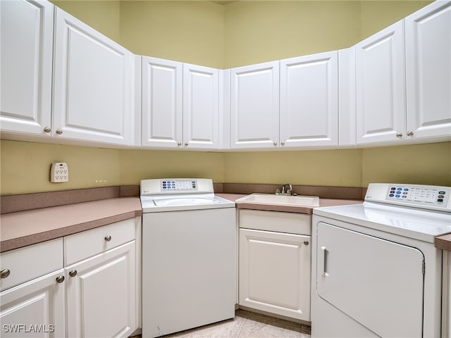 washroom with cabinets, sink, and washer and dryer