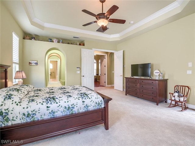 carpeted bedroom with connected bathroom, ornamental molding, a raised ceiling, and ceiling fan