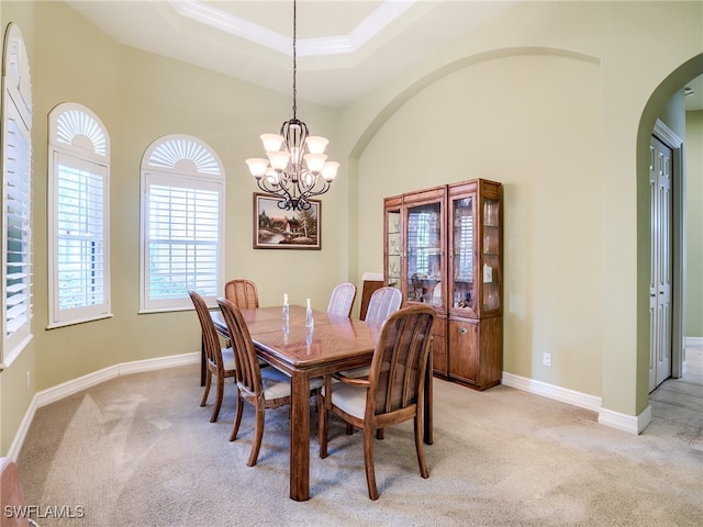 carpeted dining space with a tray ceiling and a chandelier