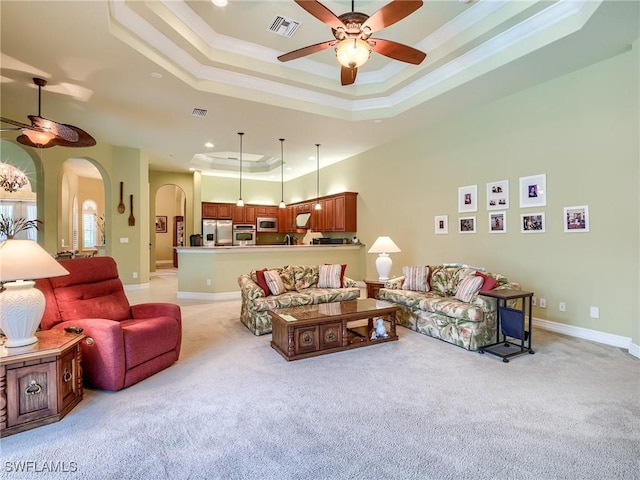 carpeted living room with crown molding, ceiling fan, and a tray ceiling