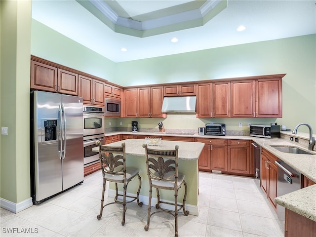 kitchen with light stone countertops, appliances with stainless steel finishes, sink, and a breakfast bar area