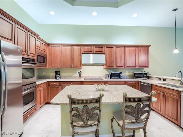 kitchen featuring appliances with stainless steel finishes, sink, pendant lighting, and a kitchen breakfast bar