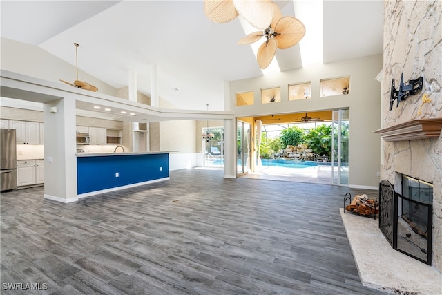 living room with wood-type flooring, sink, a fireplace, high vaulted ceiling, and ceiling fan