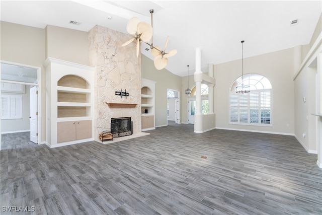 unfurnished living room with a towering ceiling, dark hardwood / wood-style floors, a fireplace, and built in features