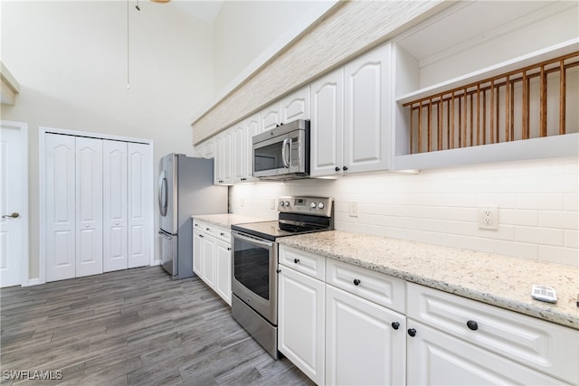 kitchen featuring light stone counters, white cabinets, tasteful backsplash, dark wood-type flooring, and appliances with stainless steel finishes