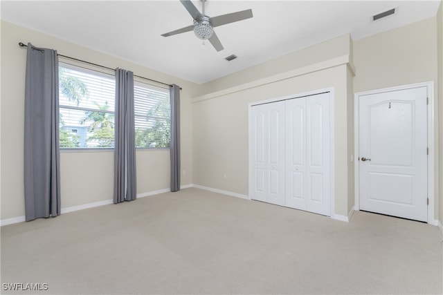 unfurnished bedroom featuring light carpet, ceiling fan, and a closet