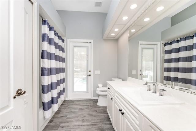 bathroom with wood-type flooring, vanity, toilet, and a shower with shower curtain