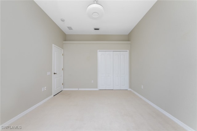 unfurnished bedroom with light carpet and a closet