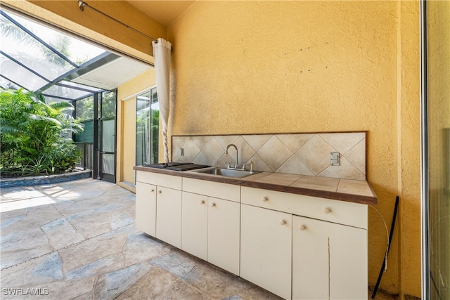 kitchen with decorative backsplash, white cabinetry, and sink