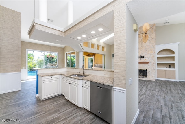 kitchen featuring sink, white cabinets, light hardwood / wood-style flooring, a large fireplace, and stainless steel dishwasher