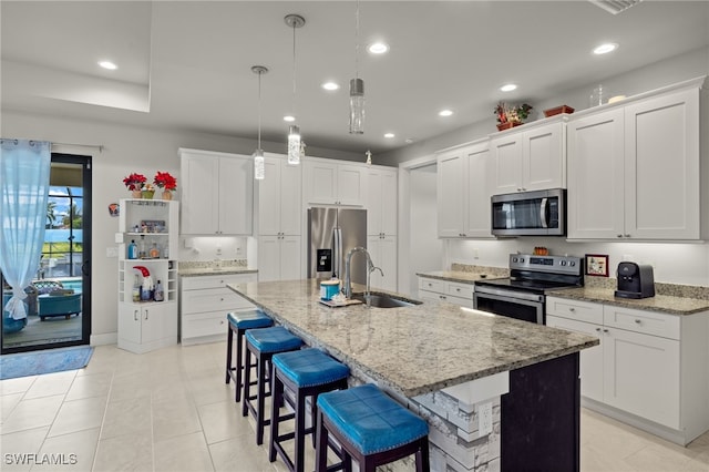 kitchen featuring a kitchen island with sink, stainless steel appliances, and white cabinetry