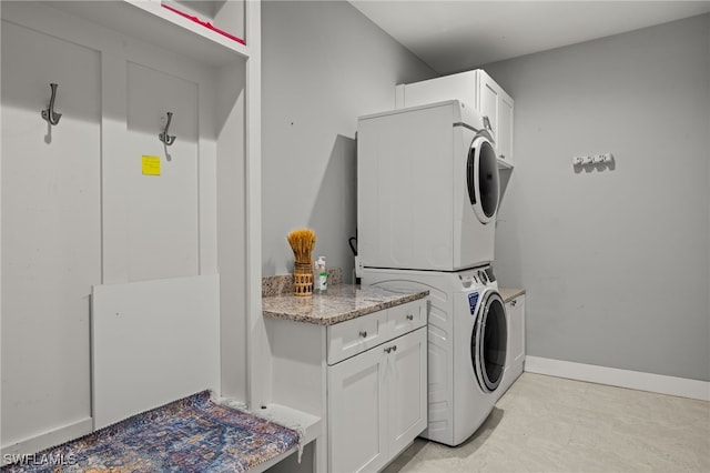 laundry area with cabinets and stacked washer and dryer