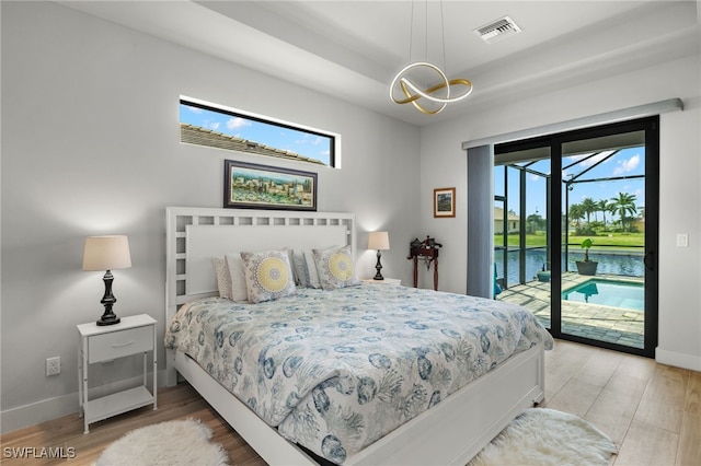 bedroom with access to outside, a water view, hardwood / wood-style floors, and multiple windows