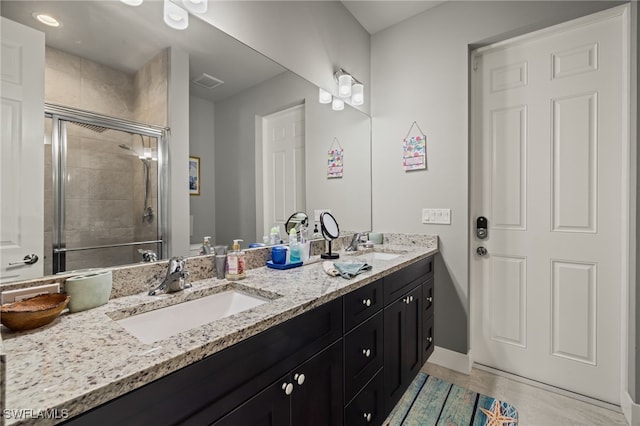 bathroom featuring tile patterned flooring, an enclosed shower, and vanity